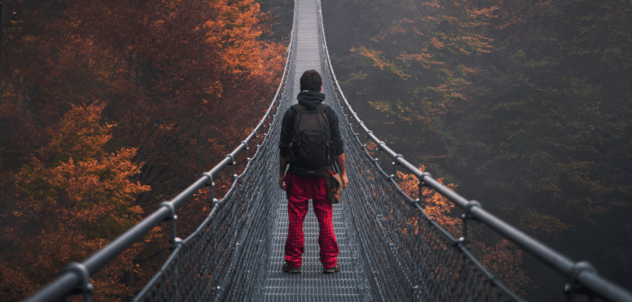 Person walking across a very long and very high pedestrian swinging bridge