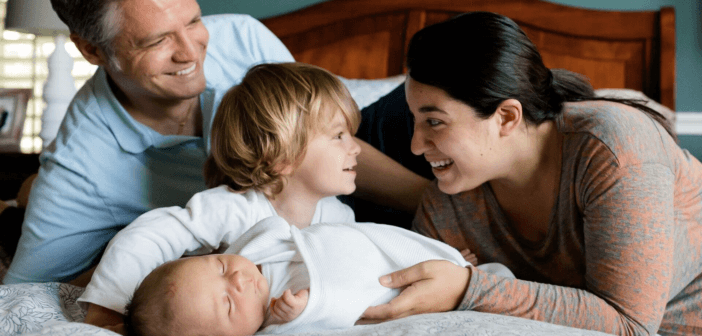 Smiling parents introducing their young smiling child to their infant