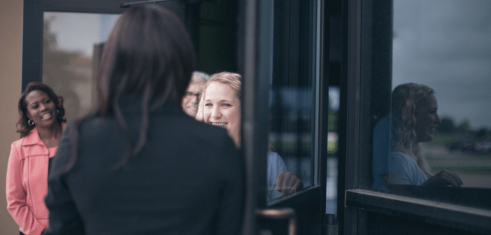 Person being warmly welcomed through a church's front doors by church memebers