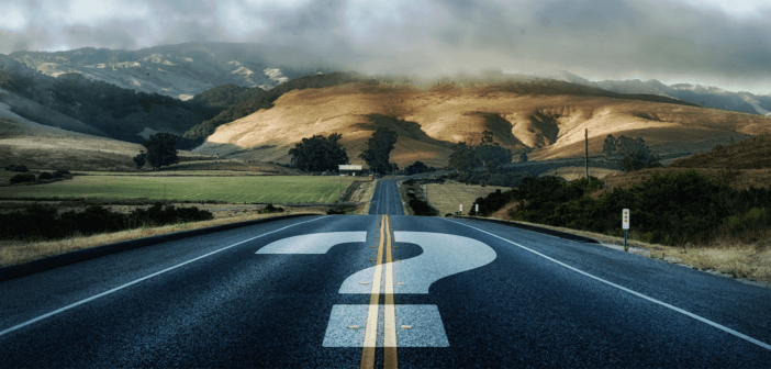 Question mark painted on a road that disappears into the horizon