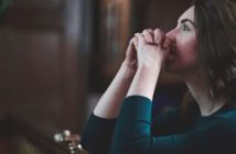 Why Pledging Still Matters Person kneeling in prayer at the front of a church sanctuary