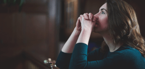 Person kneeling in prayer at the front of a church sanctuary