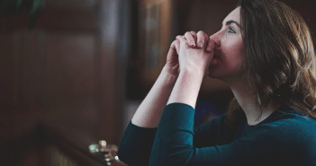 Person kneeling in prayer at the front of a church sanctuary