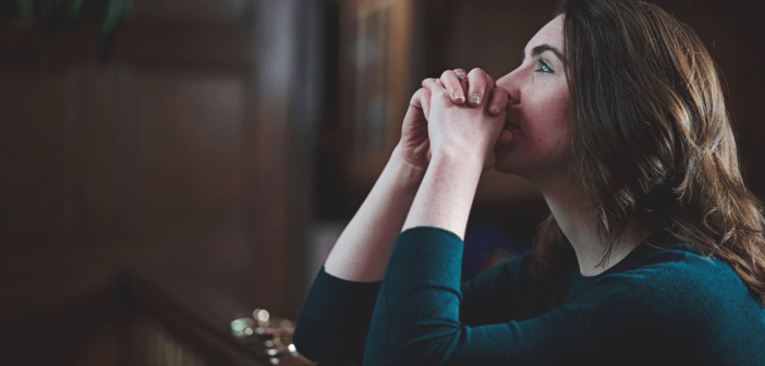 Person kneeling in prayer at the front of a church sanctuary