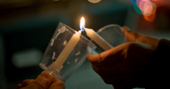 Passing the flame of a candle during a Christmas Eve service