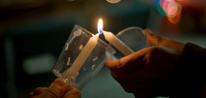 Passing the flame of a candle during a Christmas Eve service