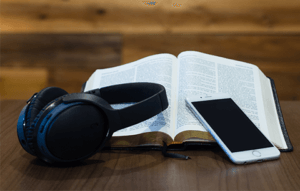 Open Bible, cell phone, and headphones