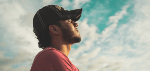 Person standing outside with eyes closed and face pointing toward the sky
