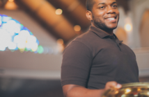 7 Strategies to Engage New Givers Smiling young adult holding an offering plate