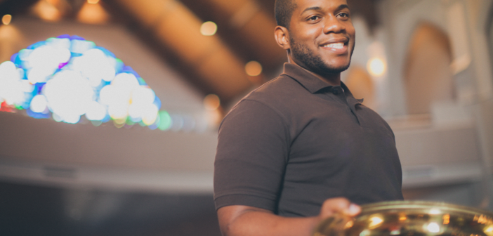 Smiling young adult holding an offering plate