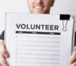 Smiling person holding up a volunteer sign-up sheet
