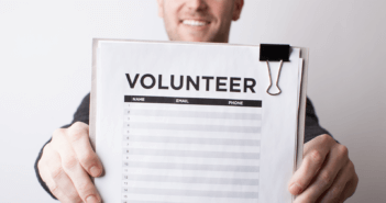 Smiling person holding up a volunteer sign-up sheet