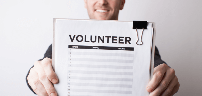 Smiling person holding up a volunteer sign-up sheet