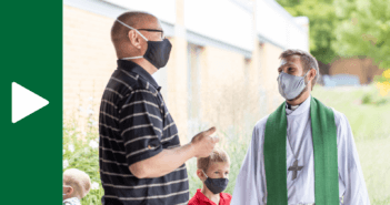 Masked pastor and church member chatting outside after church