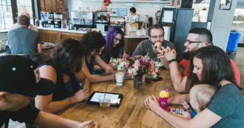 Small group in prayer while sitting around a table at a coffee shop