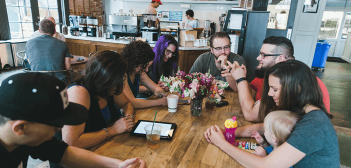 Small group in prayer while sitting around a table at a coffee shop