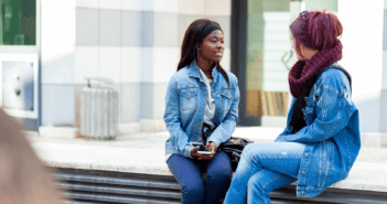 Two people having a conversation on a bench outside