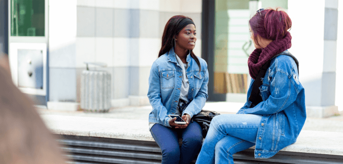 Two people having a conversation on a bench outside