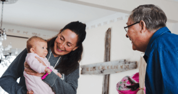 A parent showing off their baby to an older church member