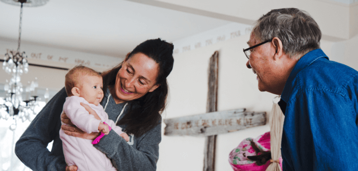 A parent showing off their baby to an older church member