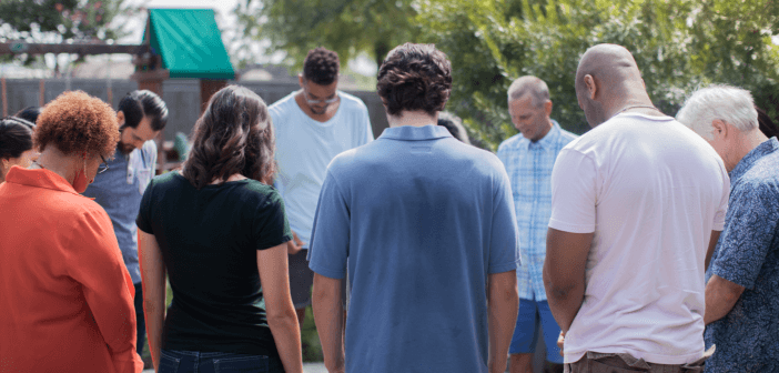 Group of people praying outdoors at a retreat