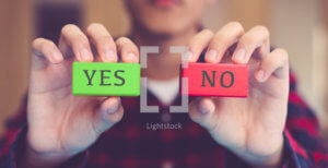 person holding up their hands with a block that says "yes" in one hand and a block that says "no" in the other