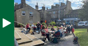 People in conversation sitting around tables set up outside of the church