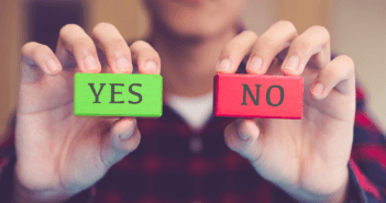 Person holding up a green block that says YES and a red block that says NO