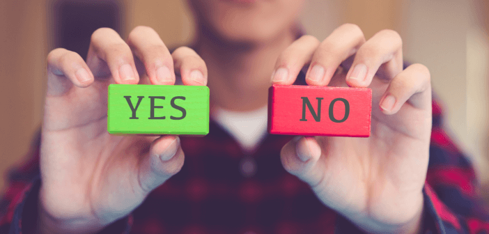 Person holding up a green block that says YES and a red block that says NO