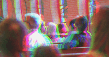 Distorted and out-of-focus image of a congregation sitting in pews