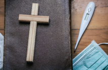 A Bible, small wooden cross, face mask, thermometer, and stethoscope