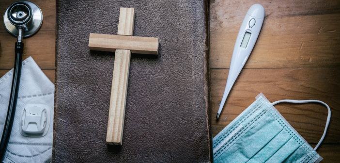 A Bible, small wooden cross, face mask, thermometer, and stethoscope