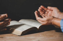 Two people praying over an open Bible