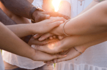 Small group of people clasping their hands together