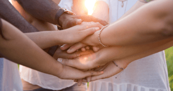 Small group of people clasping their hands together