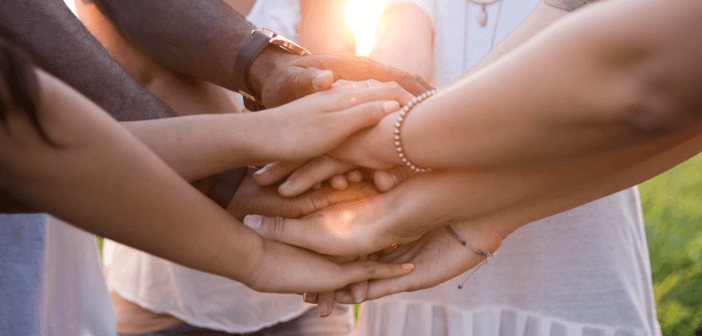 Small group of people clasping their hands together