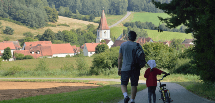 Two people walking toward a church in a small village