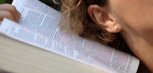 Person with their ear next to an open Bible