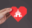 Hand holding a paper heart imprinted with a church building