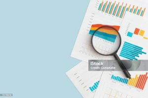 Business graphs, charts and magnifying glass on table.