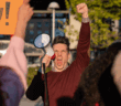 Angry protester with raised fist shouting into a megaphone