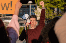 Angry protester with raised fist shouting into a megaphone
