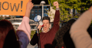 Angry protester with raised fist shouting into a megaphone