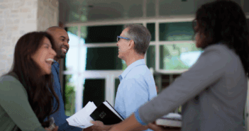 Smiling church members joyfully greeting and welcoming others at church