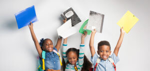 Happy children holding up their first-day-of-school supplies