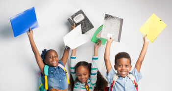 Happy children holding up their first-day-of-school supplies