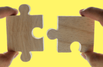Closeup of two hands joining two puzzle pieces