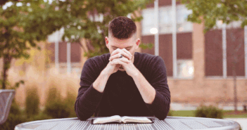 Declines in Young Clergy Reflect a Changed Culture Young pastor sitting outside praying at a table with an open Bible on it