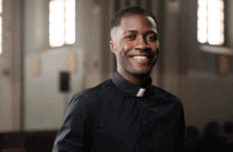 A smiling single pastor standing in the church sanctuary