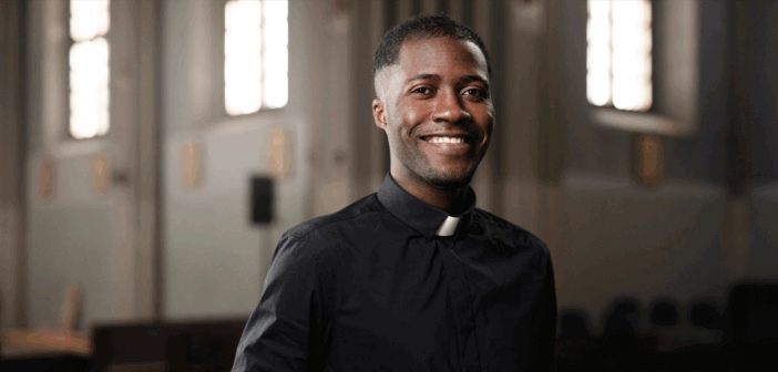 A smiling single pastor standing in the church sanctuary